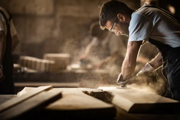  detailed image of a beginner woodworker using a hand saw to cut a piece of wood for a DIY project.